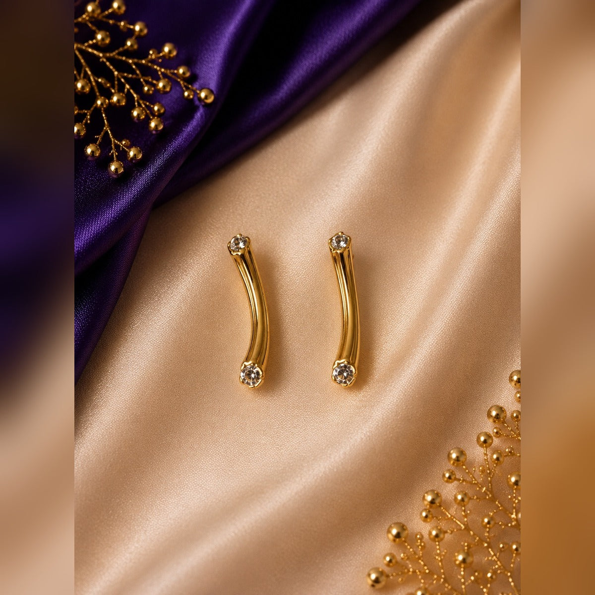 Gold curved bar stud earrings with a crystal at each end