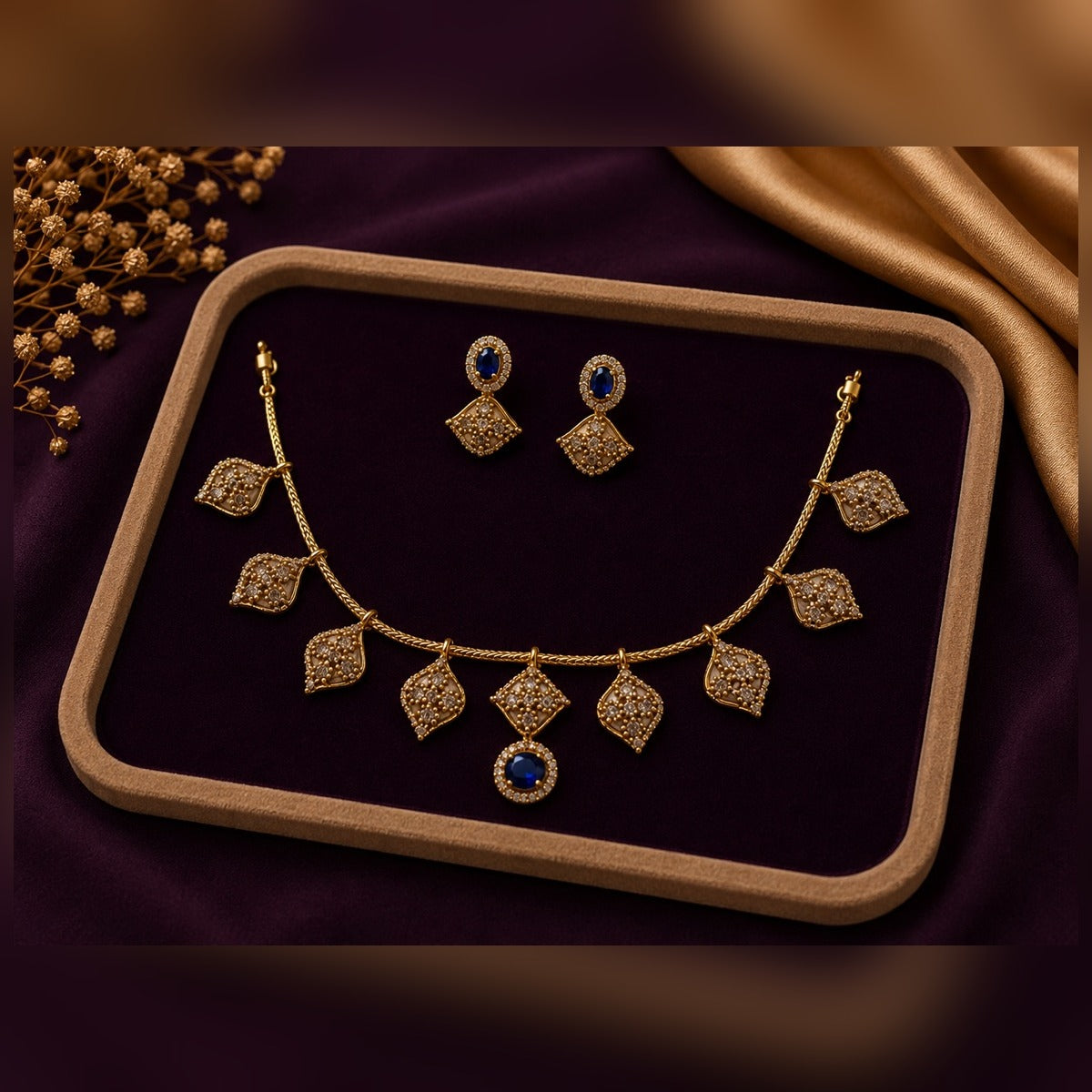 Gold necklace and earring set with pave leaf stations and blue stone drop