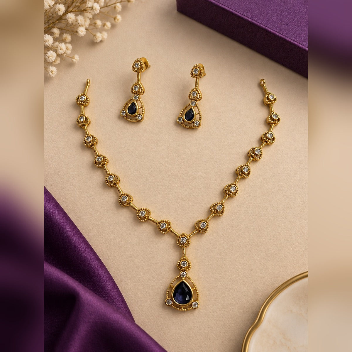 Gold-tone necklace and earring set with dark blue teardrop stones