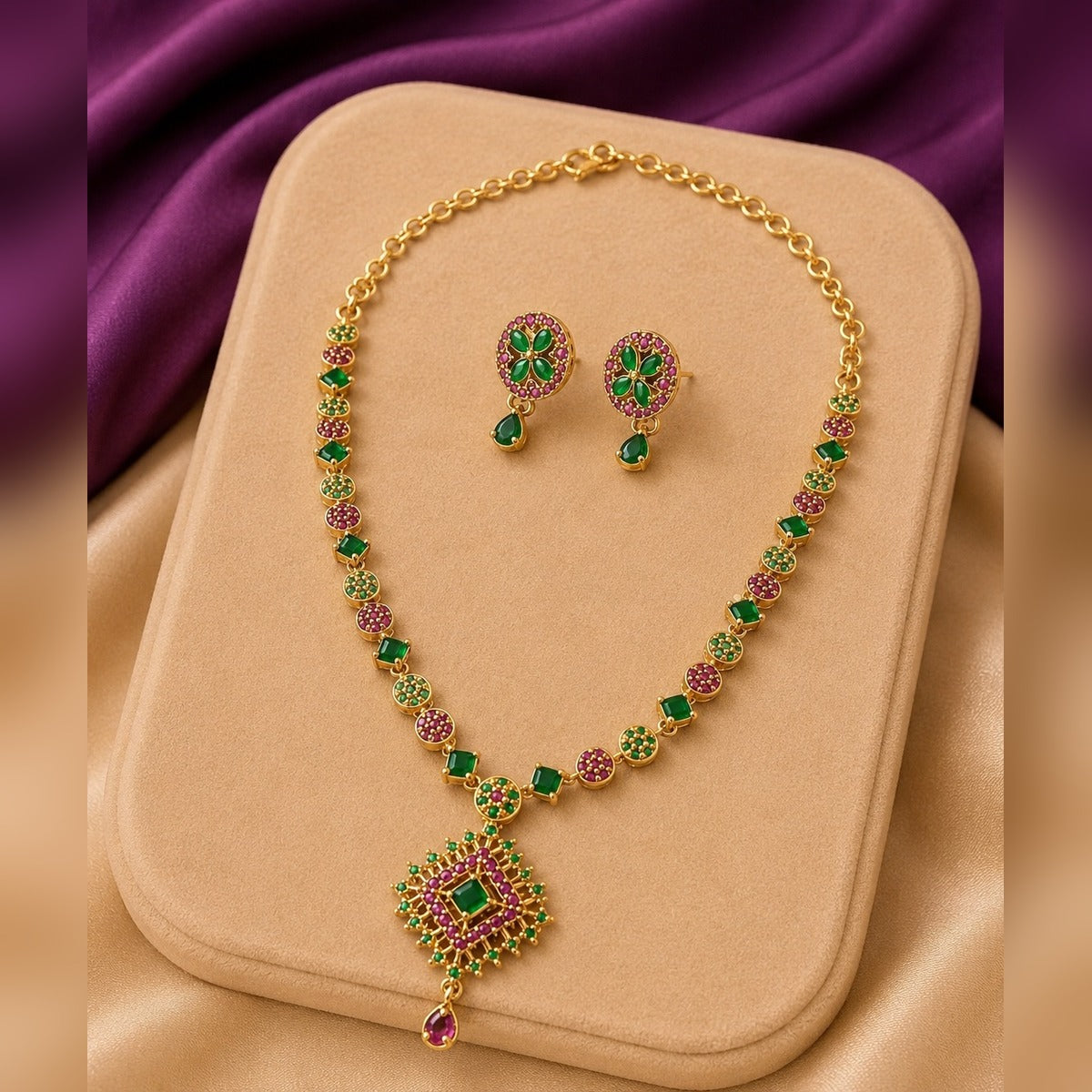 Gold necklace and earring set with ruby and green round stones and a square pendant