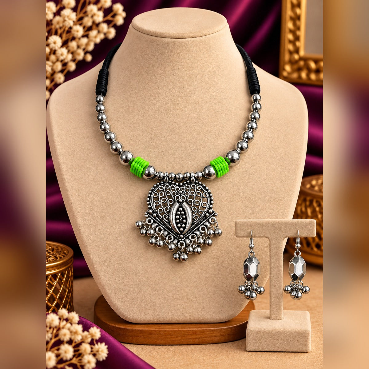 Oxidized silver heart filigree pendant necklace with green accents and ball drops, plus matching drop earrings, on a display bust