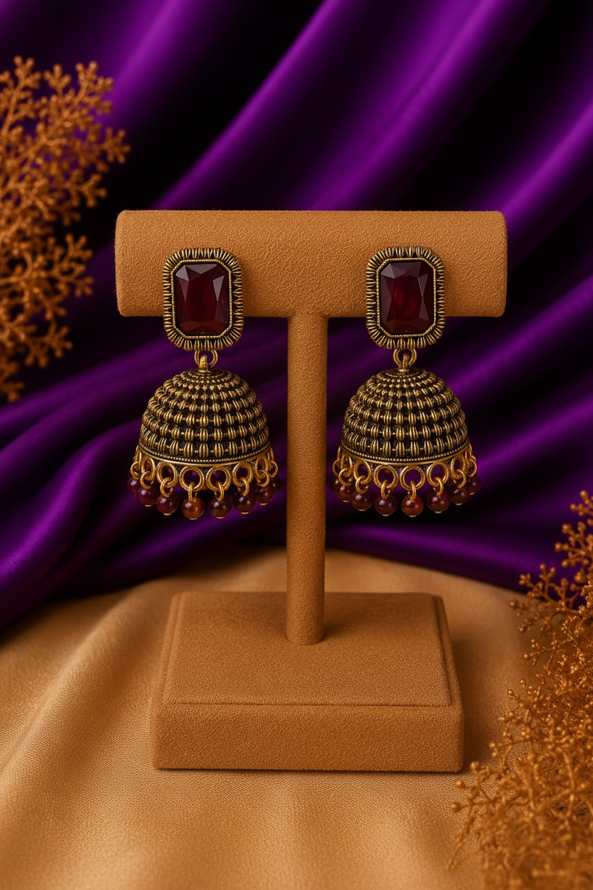 3/4 front angle view of garnet red stone wire-wrap dome jhumka earrings with bead drops