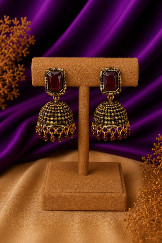 3/4 front angle view of garnet red stone wire-wrap dome jhumka earrings with bead drops
