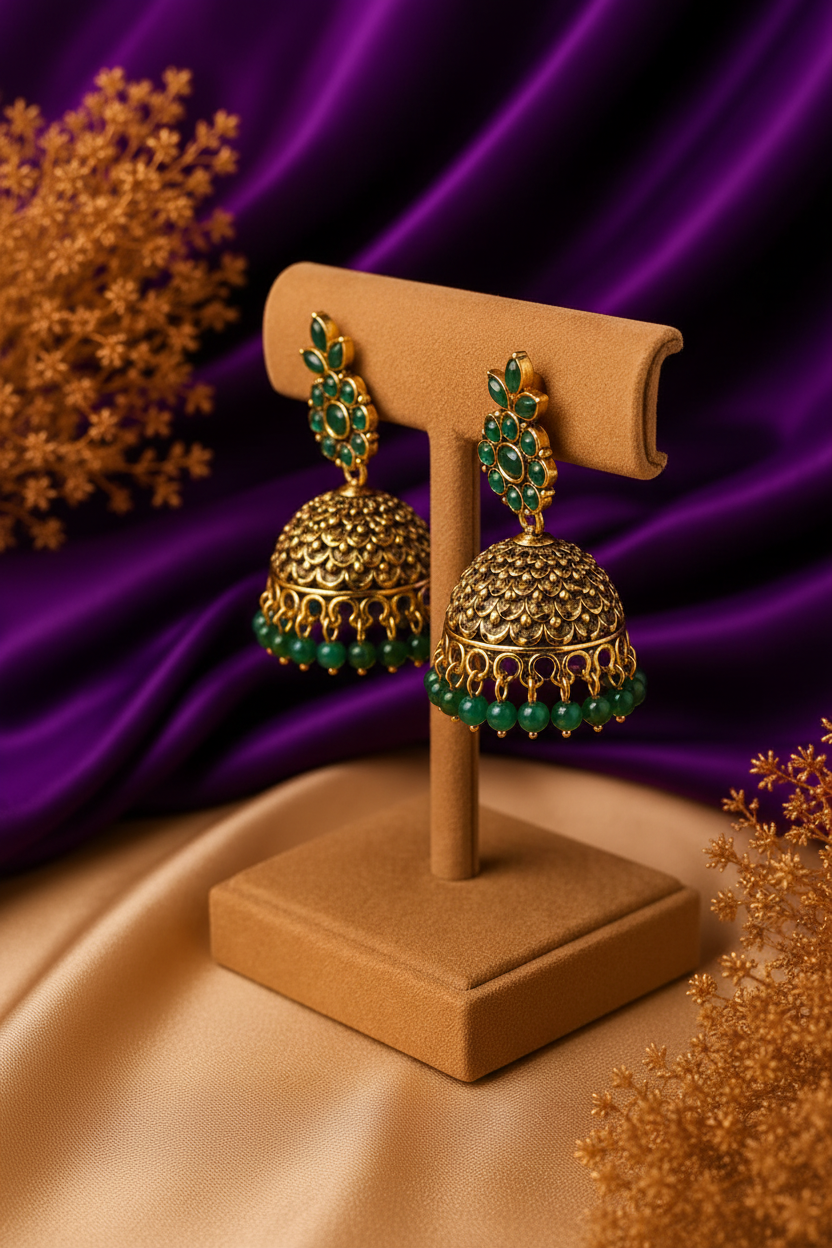 3/4 side angle view of emerald green floral cluster dome jhumka earrings with bead drops