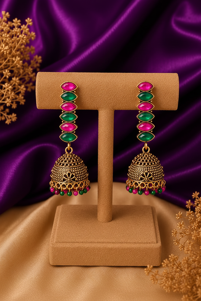 3/4 front angle view of marquise stone chain jhumka earrings with ruby and emerald stones and bead drops