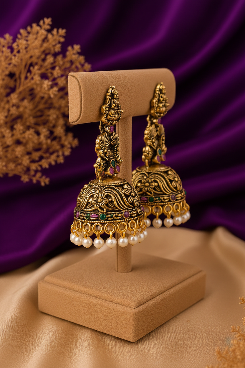 Side angle view of antique gold Lakshmi temple jhumka earrings with emerald and pink stones and pearl drops