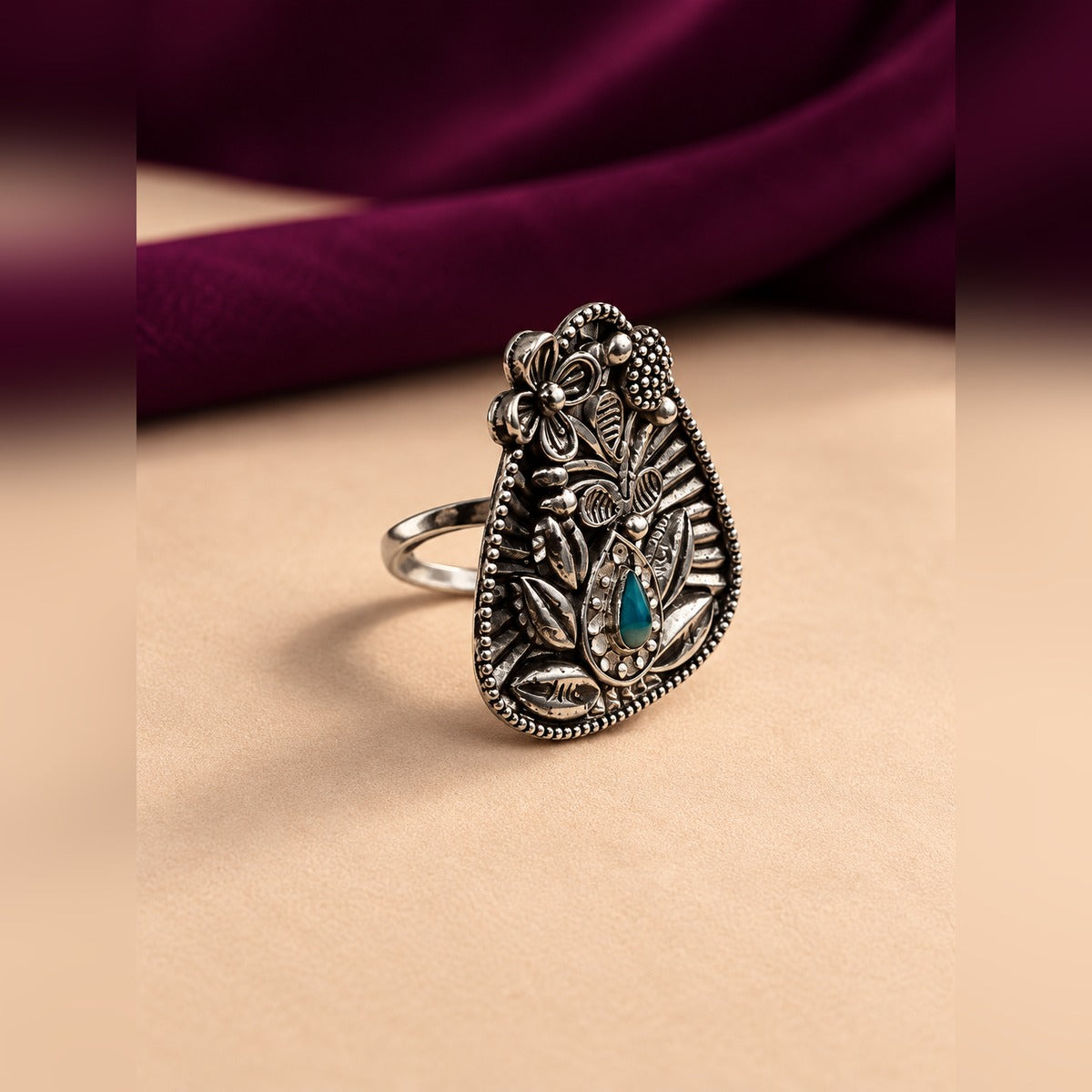 Ornate silver-tone statement ring with engraved floral face and teardrop turquoise stone